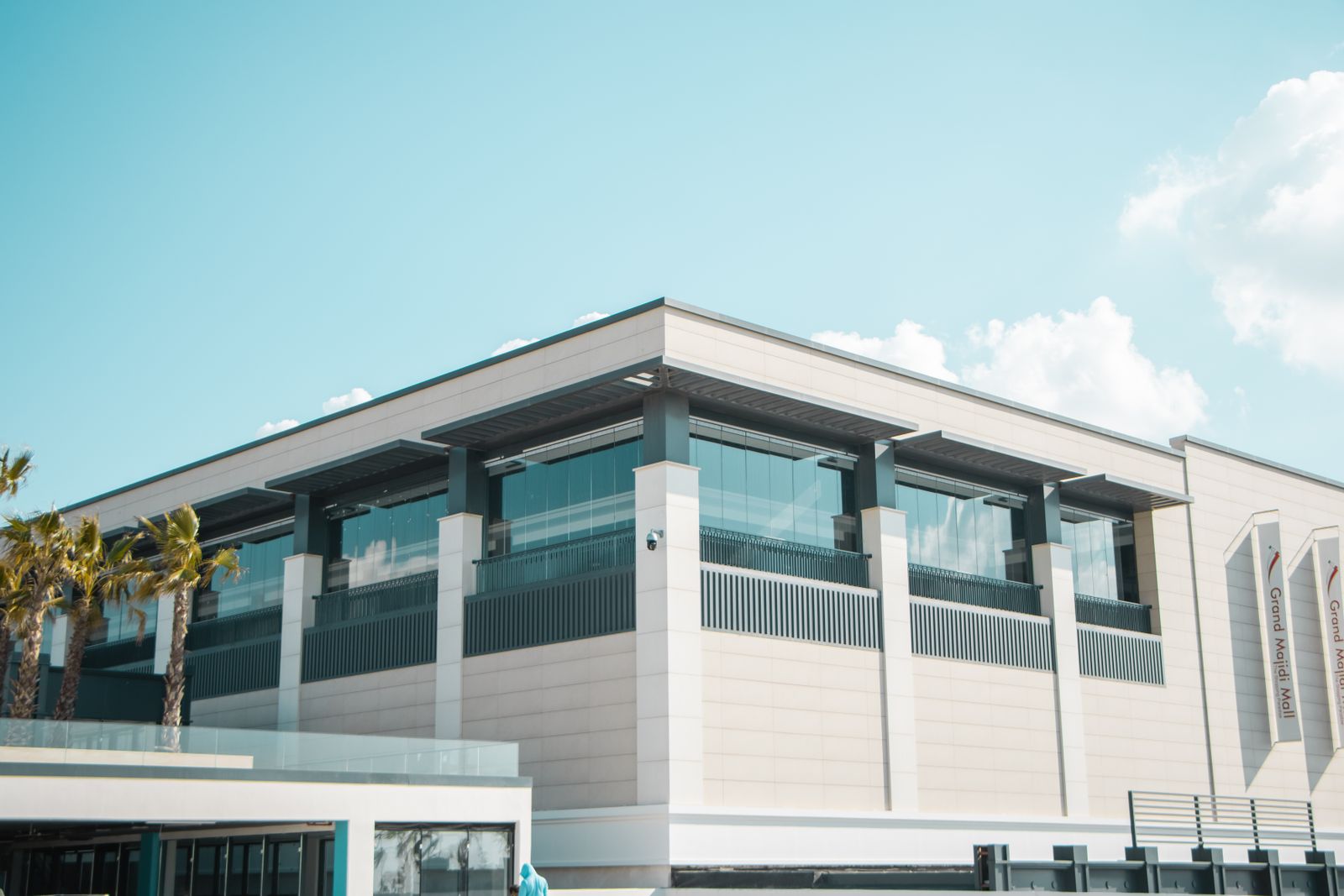 A modern commercial building with palm trees under a blue sky