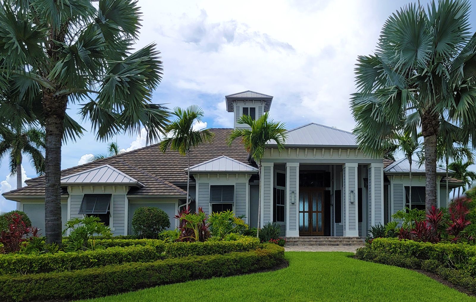 A single-story Florida home with palm trees and a green lawn